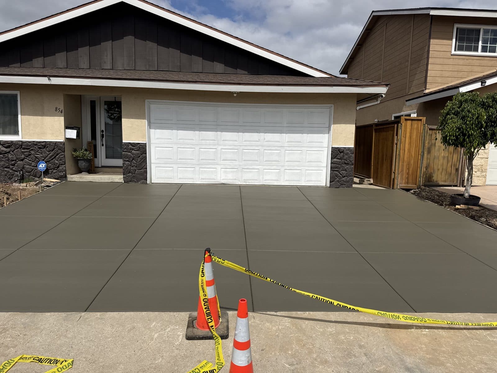 Freshly poured concrete driveway curing behind safety cones