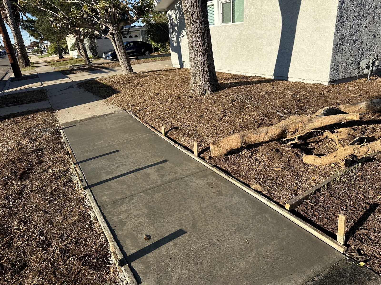 New concrete sidewalk poured alongside a block retaining wall